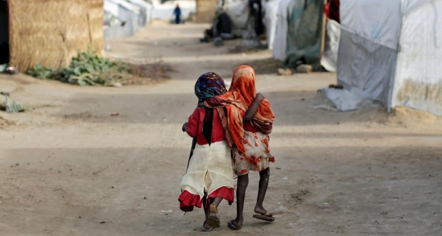 Ami and Ashbu, both three years old, walk arm in arm in the Zafaye refugee camp, some 15 kilometers from downtown N'djamena, Chad, March 11, 2015. (AP Photo)