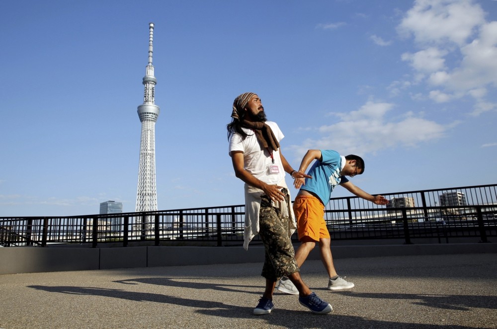 Tokuchika Nishi (L), a 38-year-old homeless man and a member of the dance group, performs with another member in front of Tokyo Sky Tree.