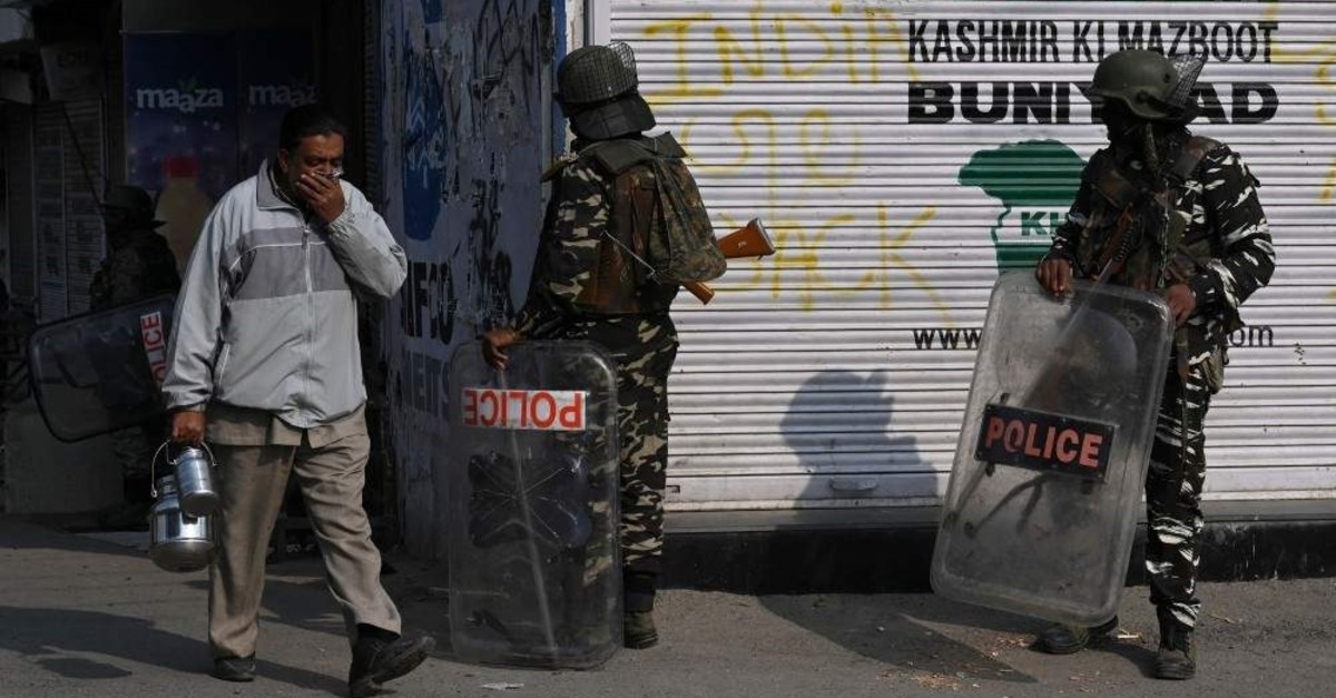 A resident walks past Indian paramilitary troopers standing guard during a lockdown, Srinagar, Oct. 29, 2019. (AFP Photo)
