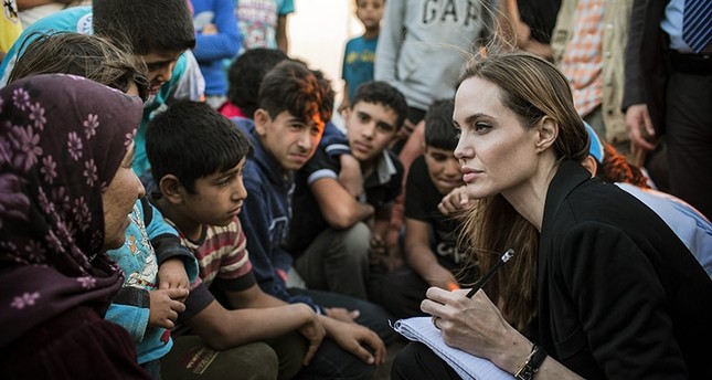This June 18, 2013 photo shows special envoy Angelina Jolie taking notes as she speaks with Syrian refugees in a Jordanian military camp based near the Syria-Jordan border. (AP Photo)