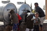 Displaced Syrians, who fled the countryside surrounding Daesh stronghold areas, are drawing water from tanks at a temporary camp in the village of Ain Issa, April 6. (AFP Photo)
