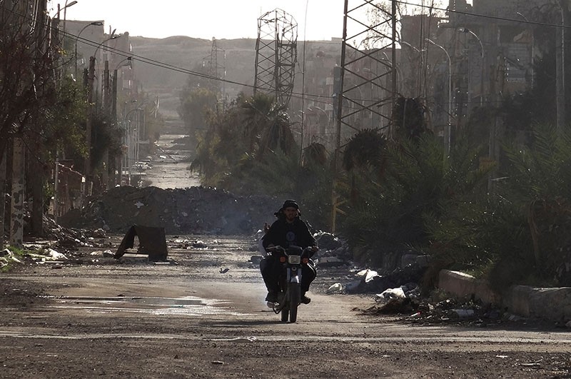 Men ride a motorbike along a deserted street filled with debris in Deir el-Zour, eastern Syria, March 7, 2014. (Reuters Photo)