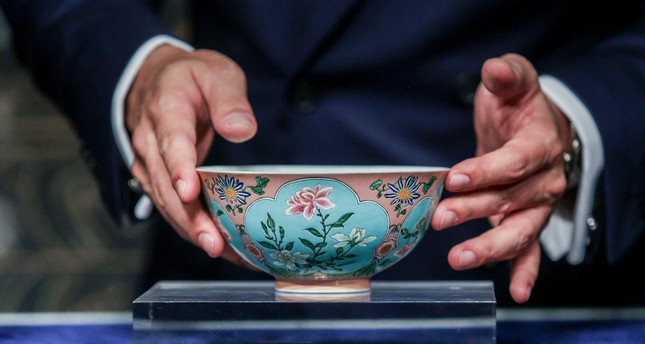 Nicolas Chow, deputy chairman for Sotheby's Asia, holds an extremely rare Qing Dynasty bowl -- one of only three known to exist -- during a media preview at Sotheby's in Hong Kong on April 3, 2018 (AFP Photo)