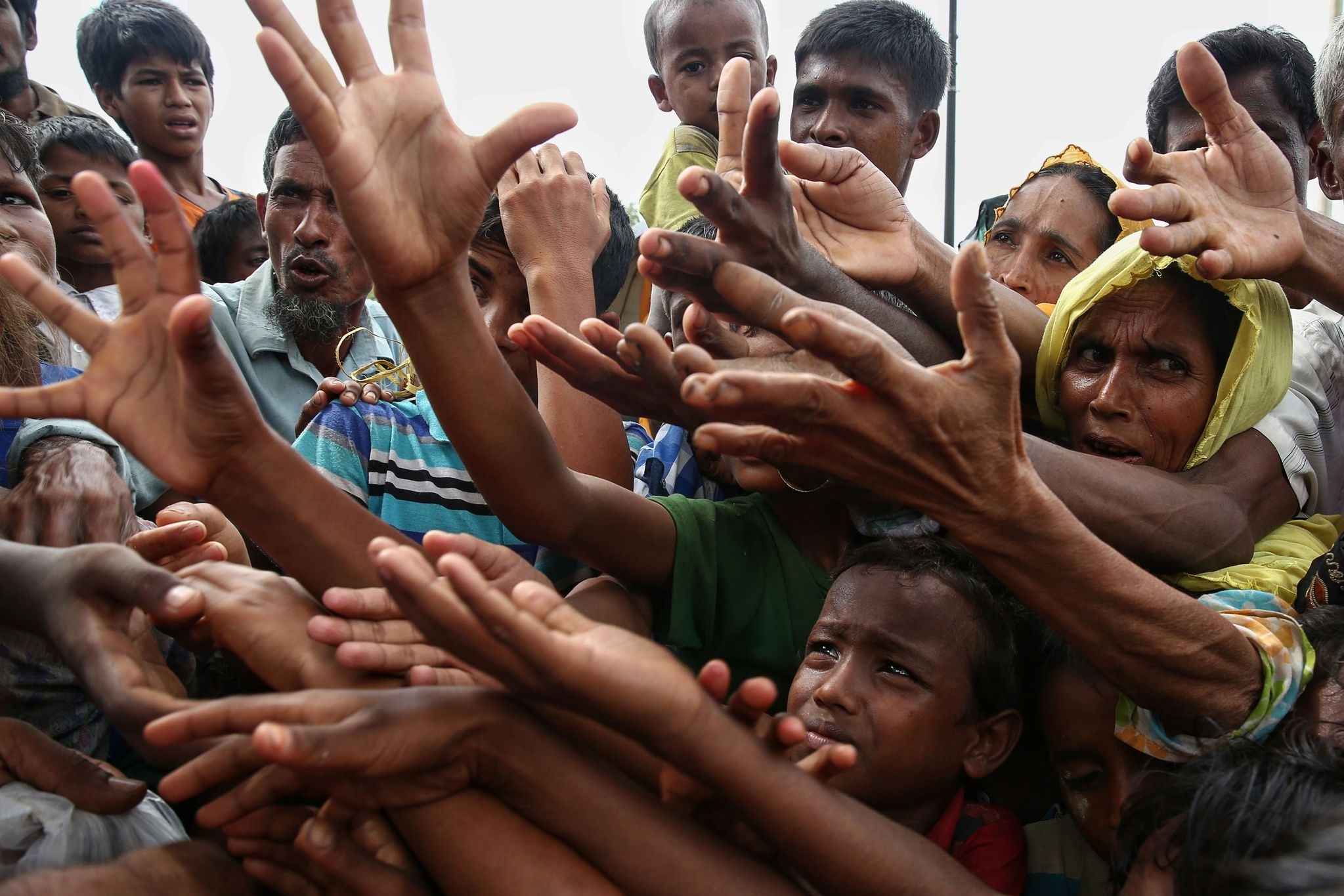Rohingya refugees reach for food aid at the Kutupalong refugee camp in Ukhiya near the Bangladesh-Myanmar border.  At least 18,500 Rohingya had crossed into Bangladesh since fighting erupted in neighboring Myanmar's Rakhine state six days earlier.