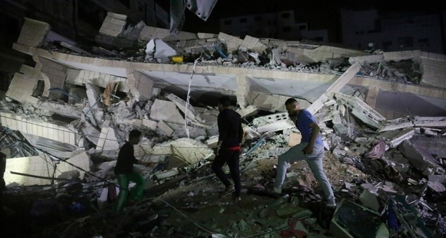 فلسطينيون بغزة يتفقدون مبنى تهدم بالكامل جراء القصف الإسرائيلي  أسوشيتد برس