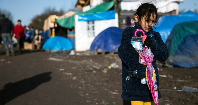 A young Kurdish girl walks along the muddy road framed with tents  and shacks in the makeshift migrant camp in grande-synthe near Dunkirk, France, Jan. 16, 2016 (EPA Photo)