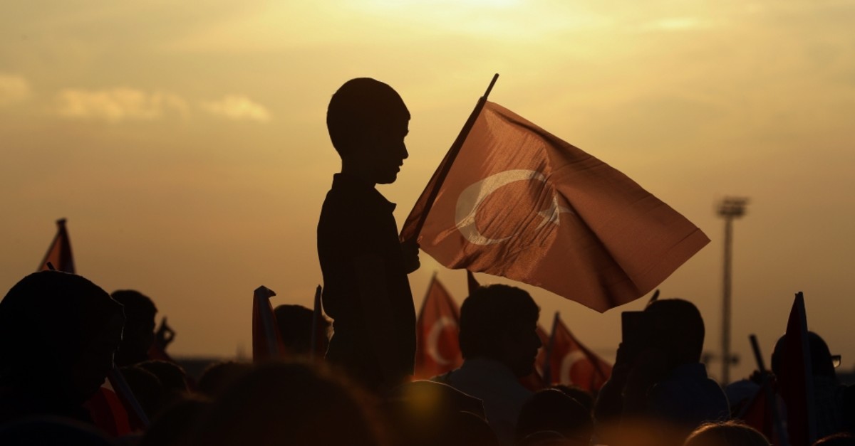 A boy holds a Turkish flag during a rally to honor the victims of the July 15, 2016 failed coup attempt, part of the ceremonies for the three-year anniversary, Istanbul, July 15, 2019.