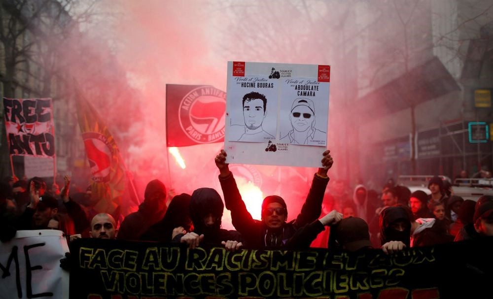 People shout slogans during a demonstration against police brutality in Paris, March 19.