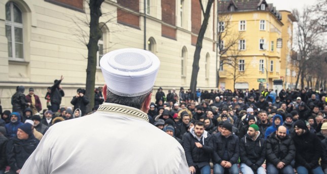 A Turkish imam addresses the Turkish-German community prior to the Friday prayer, in the street in front of the Koca Sinan Mosque, Berlin, March 16.