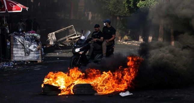 رجال يركبون دراجة نارية أمام حريق وسط اشتباكات بين الفلسطينيين والجيش الإسرائيلي في مدينة جنين بالضفة الغربية المحتلة في 4 يوليو 2023 رويترز