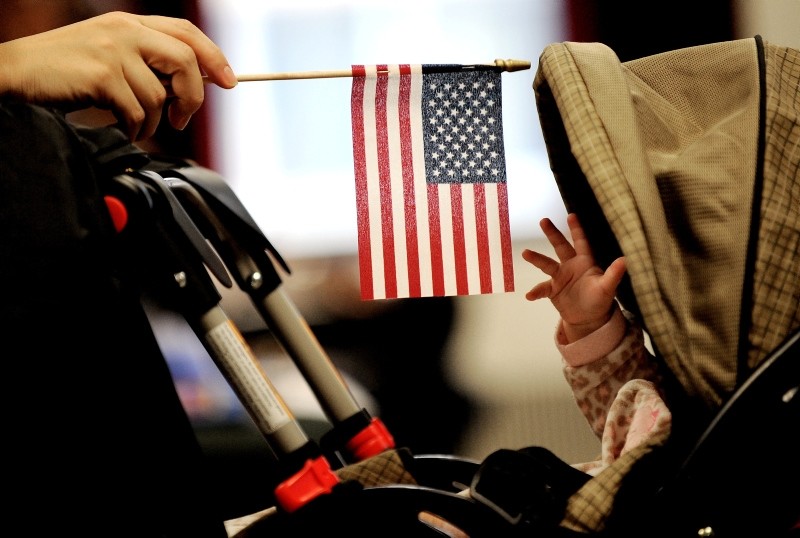 A baby reaches for an American flag held by her mother during naturalization ceremony at a federal building in New York, January 14, 2011. (EPA Photo)