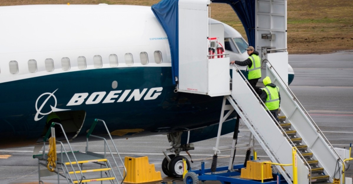 In this file photo taken on March 12, 2019 workers are pictured next to a Boeing 737 MAX 9 airplane on the tarmac at the Boeing Renton Factory in Renton, Washington. (Reuters Photo)