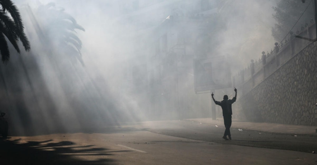 A protester gestures during clashes with police officers at a demonstration against the country's leadership, in Algiers, Friday, April 12, 2019. 