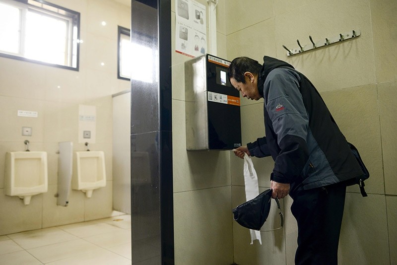 A man uses an automatic toilet paper dispenser that uses facial recognition technology at a public toilet at the Temple of Heaven in Beijing on March 21, 2017. (AFP Photo)