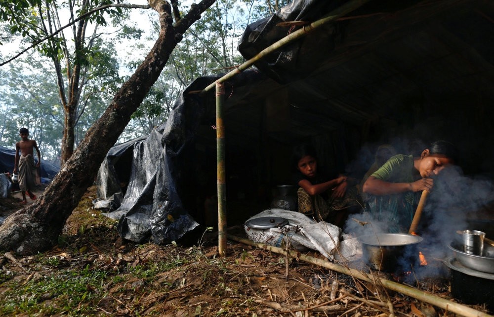 A Rohingya refugee cooks food in her temporary shelter at the Kutupalong makeshift refugee camp in Cox's Bazar, Bangladesh, Sept.14. 