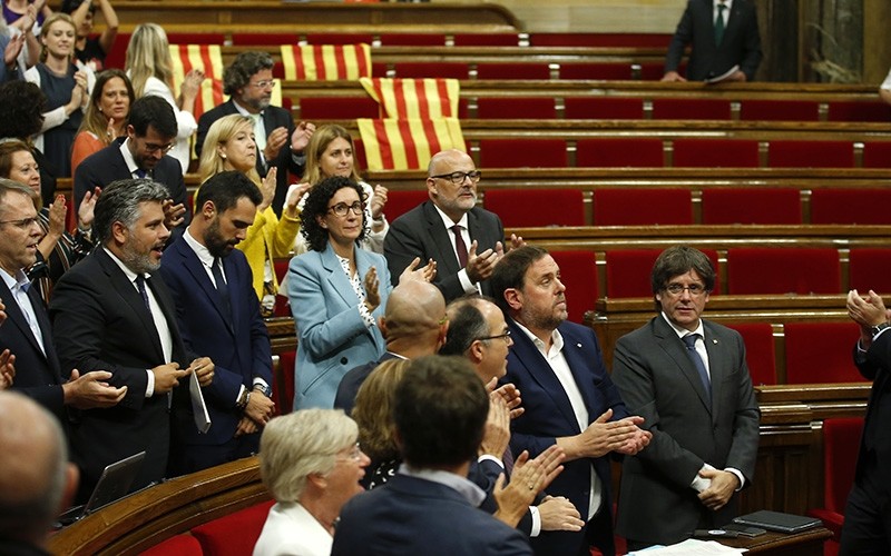 Catalonia regional President Carles Puigdemont, right, stands with others parliamentarians on their seats, after the voting during a plenary session at the Parliament of Catalonia in Barcelona, Spain, Wednesday, Sept. 6, 2017 (AP Photo)