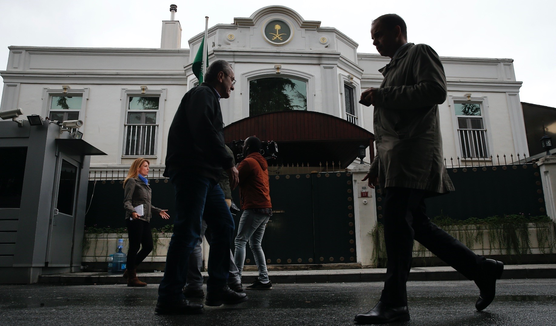 Pedestrians walk by as members of the media report from outside the consul general of Saudi Arabiau2019s residence in Istanbul, Oct. 18.
