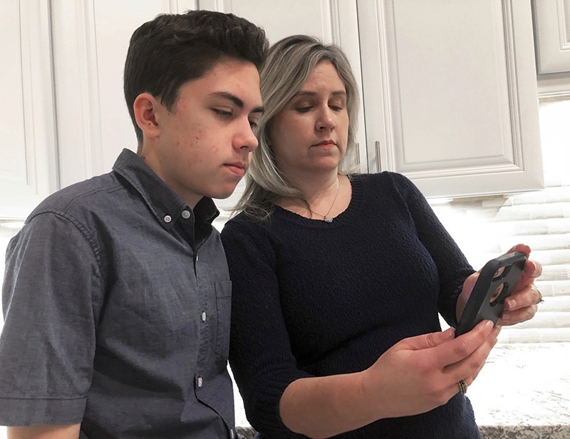 In this Jan. 31, 2019, file photo Grant Thompson and his mother, Michele, look at an iPhone in the family's kitchen in Tucson, Ariz., on Thursday, Jan. 31, 2019. (AP Photo)