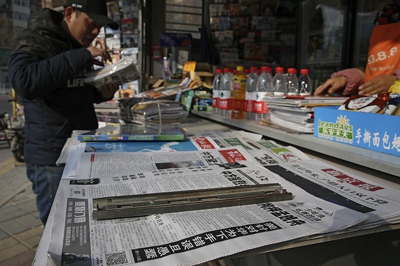 A man arranges magazines near newspapers with the headlines of China outcry against U.S. on the detention of Huawei's chief financial officer, Meng Wanzhou, at a news stand in Beijing, Monday, Dec. 10, 2018. (AP Photo)