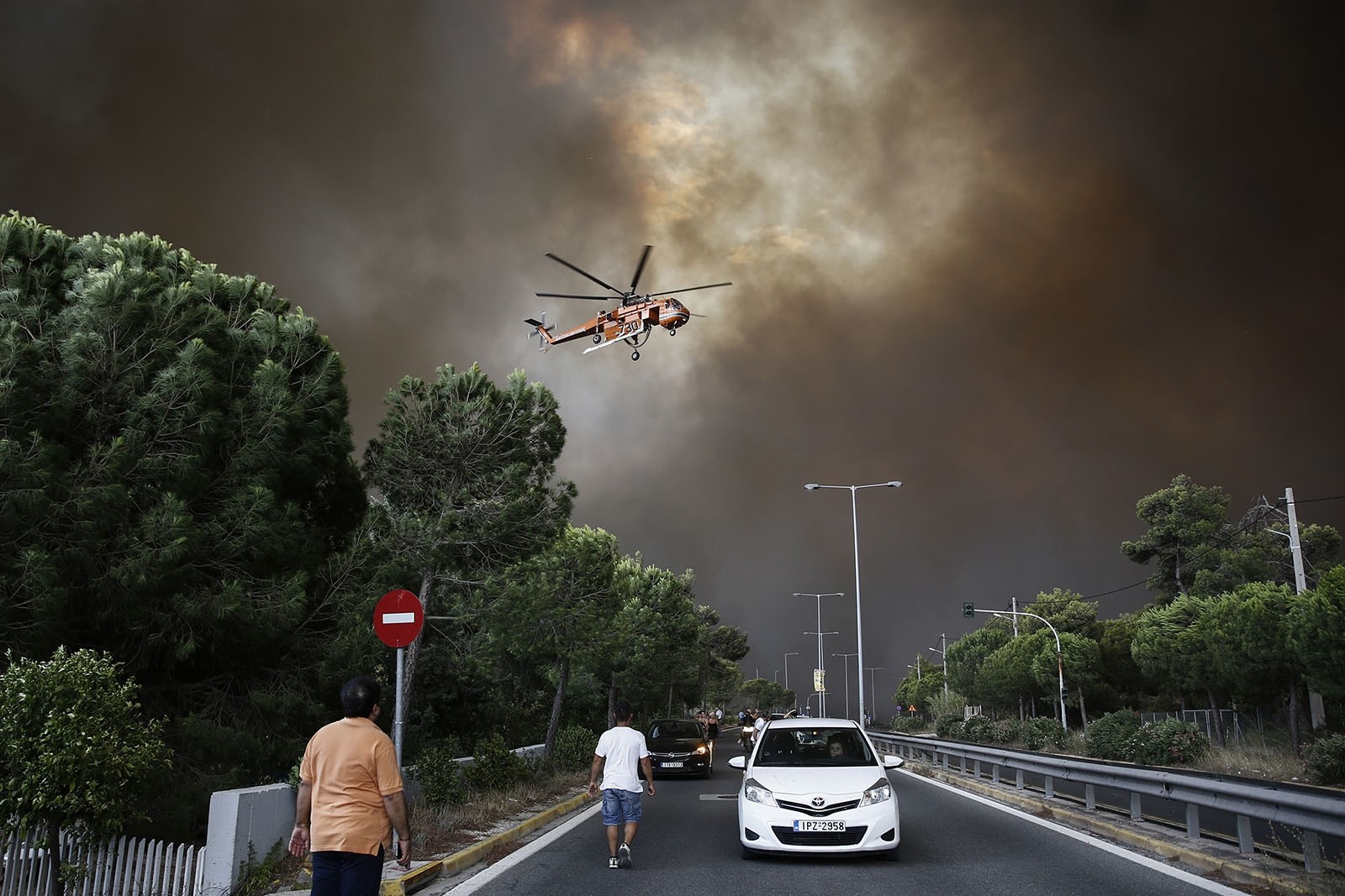 A firefighting helicopter flies over an avenue during a forest fire in Neo Voutsa, a northeast suburb of Athens, Greece, July 23, 2018. 