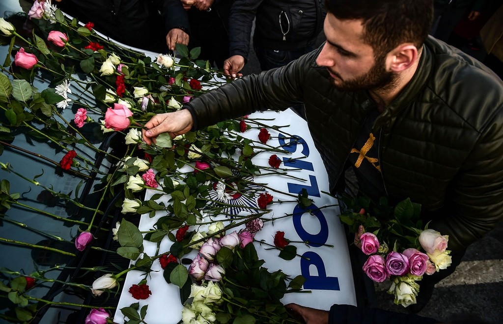 A man lays flowers on a police vehicle as people pay their respects outside the Vodafone Arena football stadium in Istanbul on December 11, 2016 (AFP Photo)