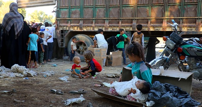 A picture taken on August 4, 2017 shows displaced Syrian children, who fled from Daesh's Syrian stronghold of Raqqa, receiving humanitarian aid delivered by UNICEF at a temporary camp (AFP Photo)
