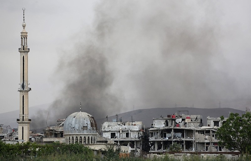Smoke billows behind destroyed buildings in the former rebel-held town of Saqba in the eastern Ghouta region on the outskirts of Damascus on April 10, 2018. (AFP Photo)