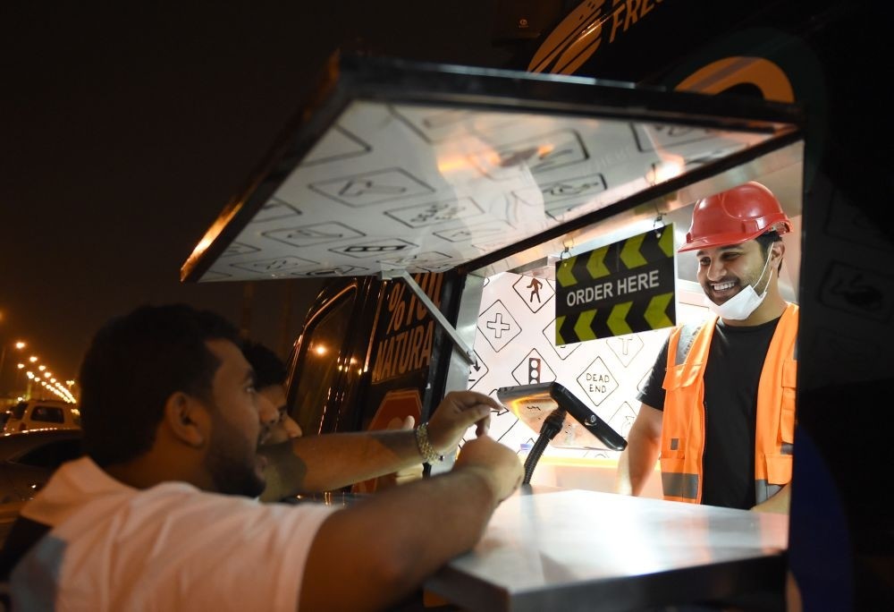 Bader al-Ajmi, 38,(R) owner of ,One Way Burger, serves customers from his truck at a main street in the capital Riyadh.