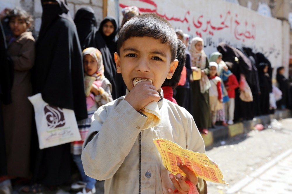 A conflict-affected child eats a loaf of bread after receiving food from a local charity, Sanaa, Nov. 3.