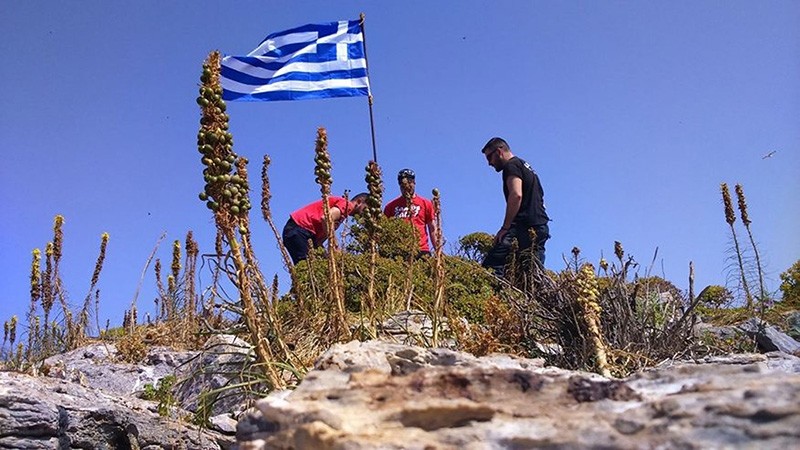 Unidentified individuals hoisting a Greek flag on an islet off Turkey's Didim coast (Sabah Photo)