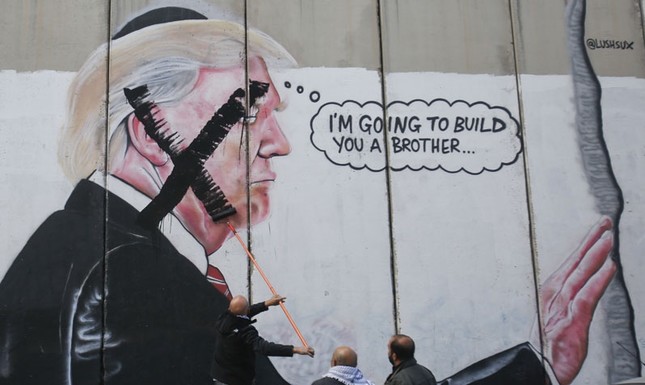 A Palestinian paints over a mural of President Trump during a protest in Bethlehem, the West Bank, Dec. 7, 2017. (AP Photo)