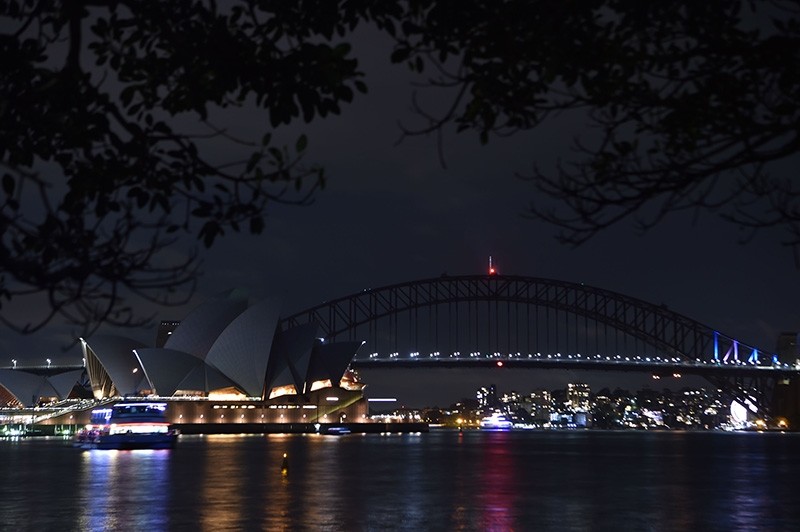 Sydney Harbour Bridge and the Opera House are plunged into darkness for the Earth Hour environmental campaign on March 24, 2018 (AFP Photo)