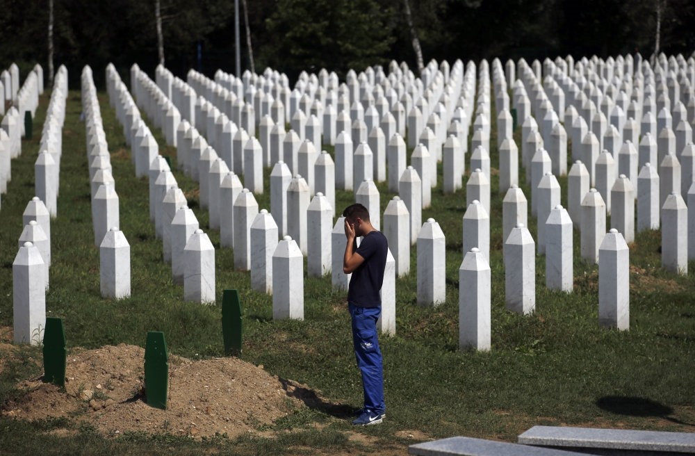 A man prays among gravestones at the memorial center of Potocari near Srebrenica, Bosnia-Herzegovina, Aug. 14, 2018.