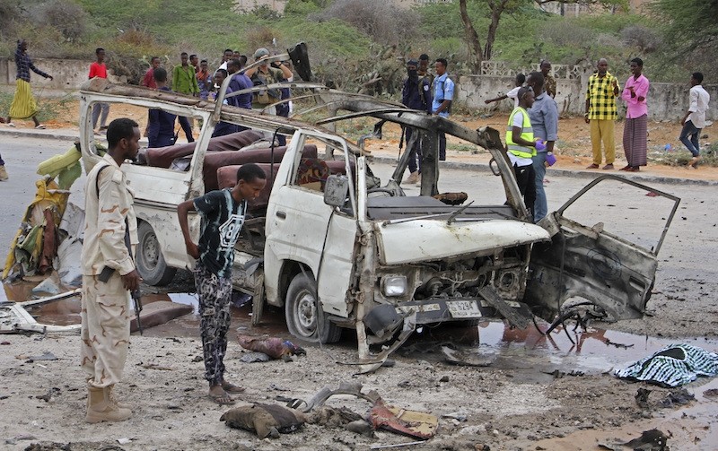 A Somali soldier, left, stands by the wreckage of a passing minibus that was destroyed in a suicide car bomb attack near the defense ministry compound in Mogadishu, Somalia Sunday, April 9, 2017. AP Photo