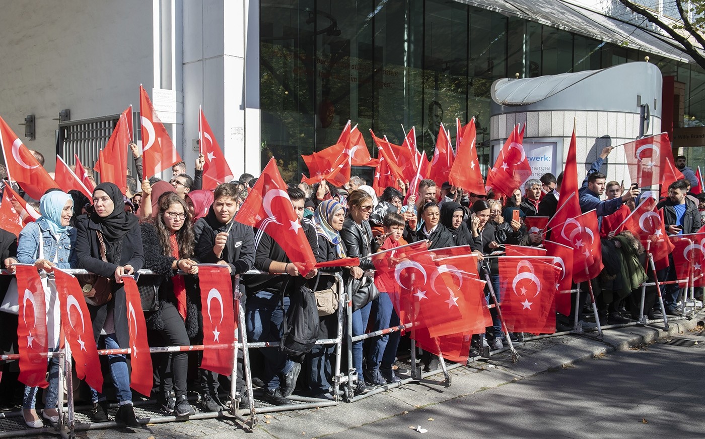 Fans of Turkish President Recep Tayyip Erdoğan hold Turkish flags while waiting for his arrival to a hotel in Berlin Thursday, Sept. 27, 2018. (AP Photo)