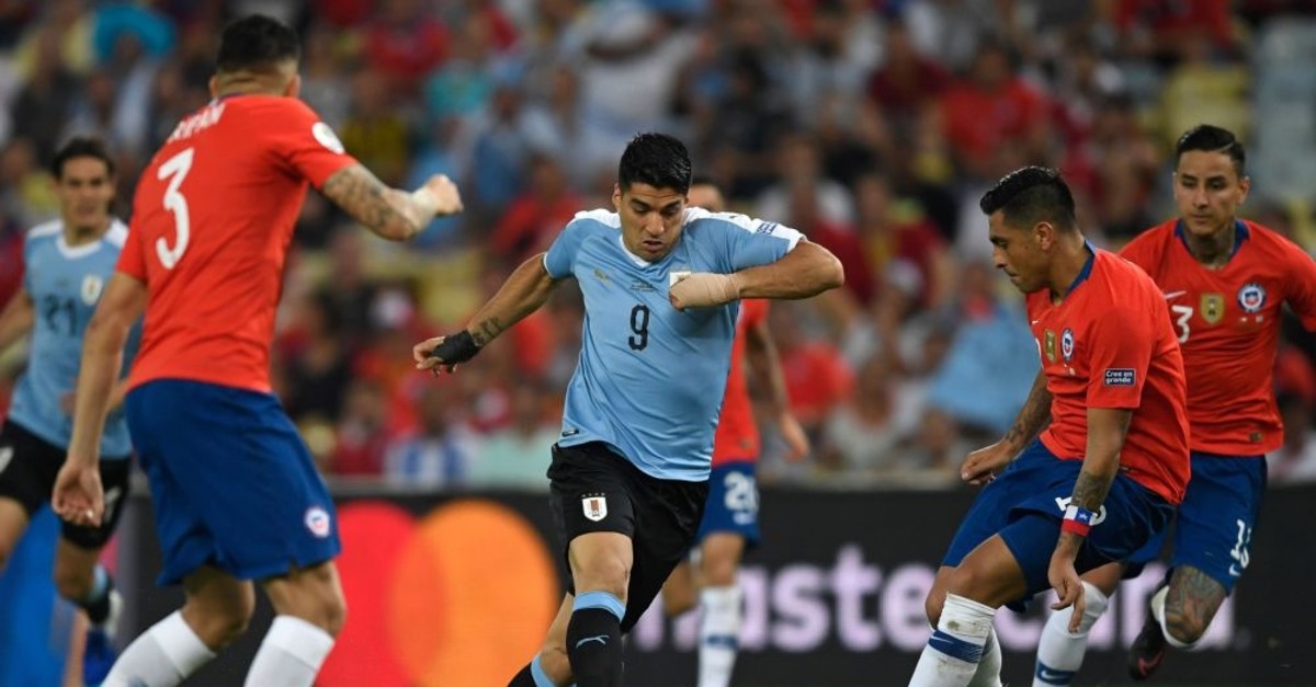 Uruguay's Luis Suarez (C) is marked by Chile's Gonzalo Jara (R) during the match in Rio de Janeiro, Brazil, June 24, 2019.