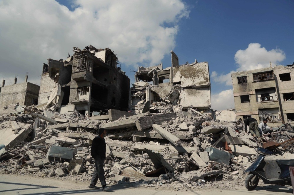 A Syrian man walks past buildings destroyed earlier in regime air strikes in the besieged opposition-held town of Douma in the Eastern Ghouta region on the outskirts of the capital, Damascus, Feb. 28.