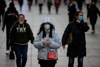 People wearing protective face masks walk along a street, Shanghai, Feb. 19, 2020. (AFP Photo)