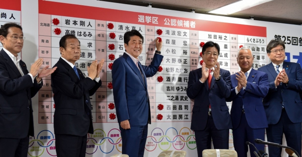 Japanese PM and ruling Liberal Democratic Party (LDP) president Shinzo Abe (3rd L) celebrates as he attaches paper flowers on the winning candidates of the Parliament's upper house election at the party's headquarters in Tokyo on July 21, 2019. (AFP)