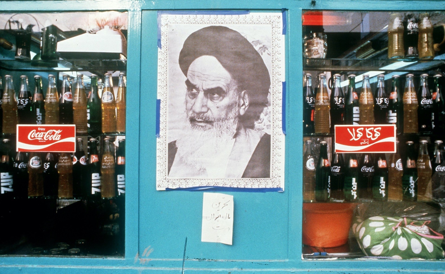 A poster of Iranian leader Ayatollah Khomeini in a shop window next to bottles of Coca-Cola, Tehran, Jan. 1, 1979.