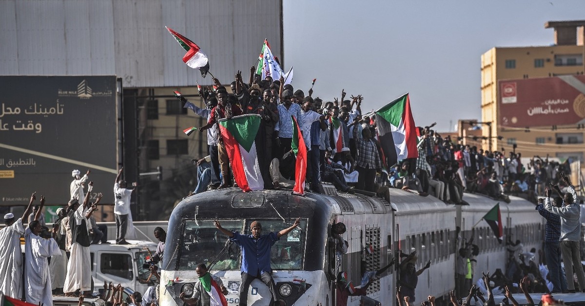 Sudanese protesters from the city of Atbara, sitting atop a train, cheer upon arriving at the Bahari station in Khartoum, April 22, 2019.
