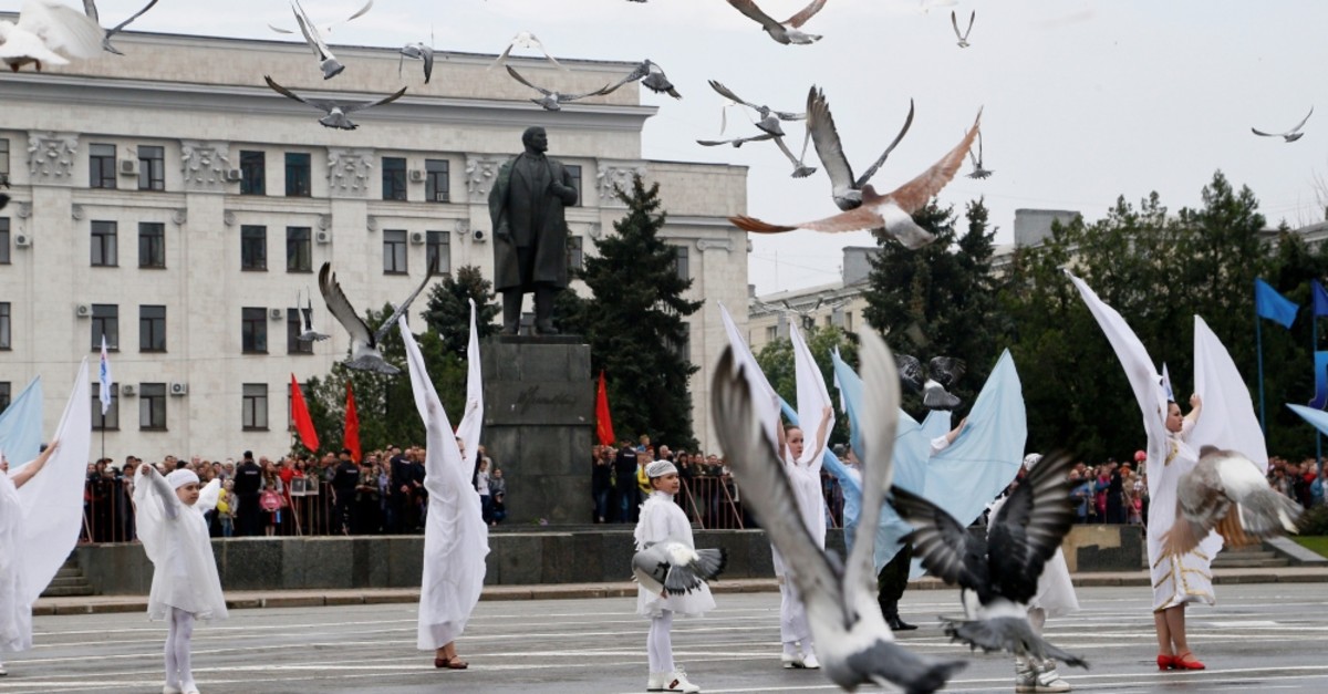 People take part in Victory Day celebrations to mark the defeat of Nazi Germany in World War II, as pigeons fly above in the rebel-controlled city of Luhansk, Ukraine, May 9, 2019.