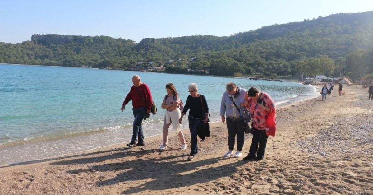 Tourists enjoy a peaceful walk on the beach while others take a dip, Antalya, Dec. 5, 2019. (DHA Photo)