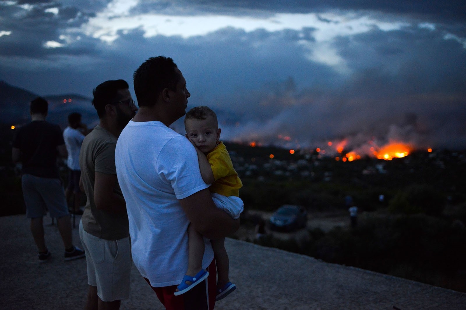 A man holds his son as a wildfire burns in the town of Rafina, near Athens, July 23, 2018.  