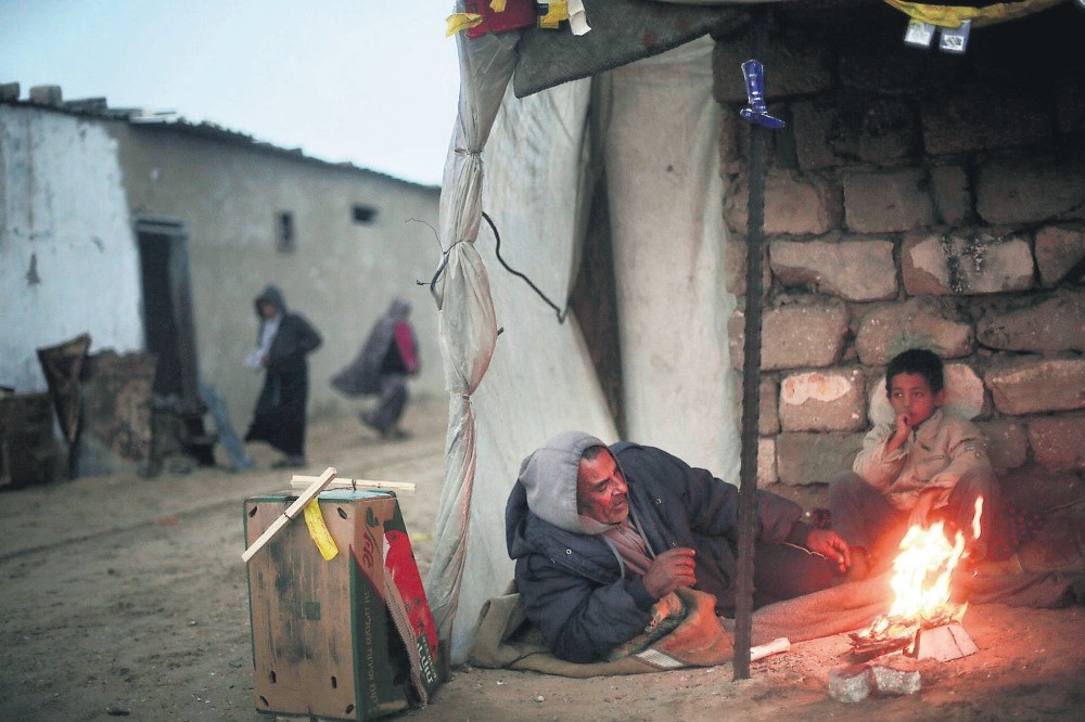 A Palestinian man and his son warm themselves during cold, rainy weather in a slum on the outskirts of the Khan Younis refugee camp, southern Gaza Strip, Jan. 5.
