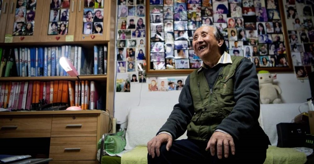 This photo taken on Dec. 17, 2019 shows matchmaker Zhu Fang smiling at his house with walls covered with images of single women who have come to him over the years in Beijing. (AFP Photo)