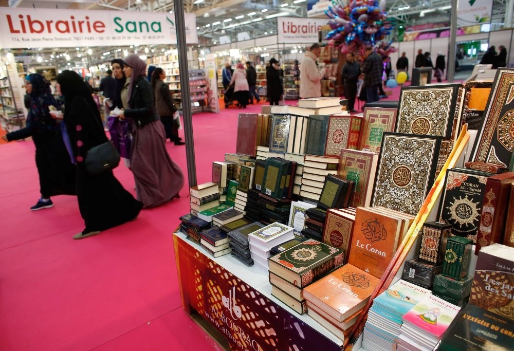 Visitors walking past a bookseller displaying copies of the Quran during the 32nd Annual Meeting of France's Muslims, at Le Bourget Exhibition center, north of Paris, April 3, 2015.
