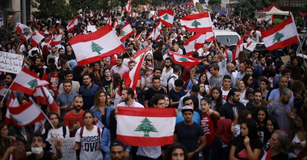 Demonstrators chant slogans against the Lebanese government as they hold Lebanese national flags during a protest in Beirut, Lebanon, Oct. 26, 2019. AP
