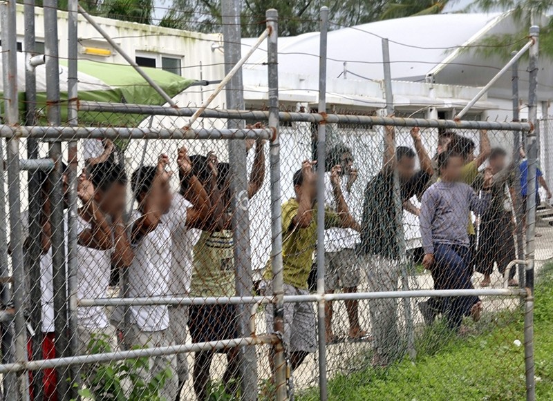 Asylum seekers staring at media from behind a fence at the Oscar compound in the Manus Island detention center, Papua New Guinea, March 21, 2014. (EPA Photo)