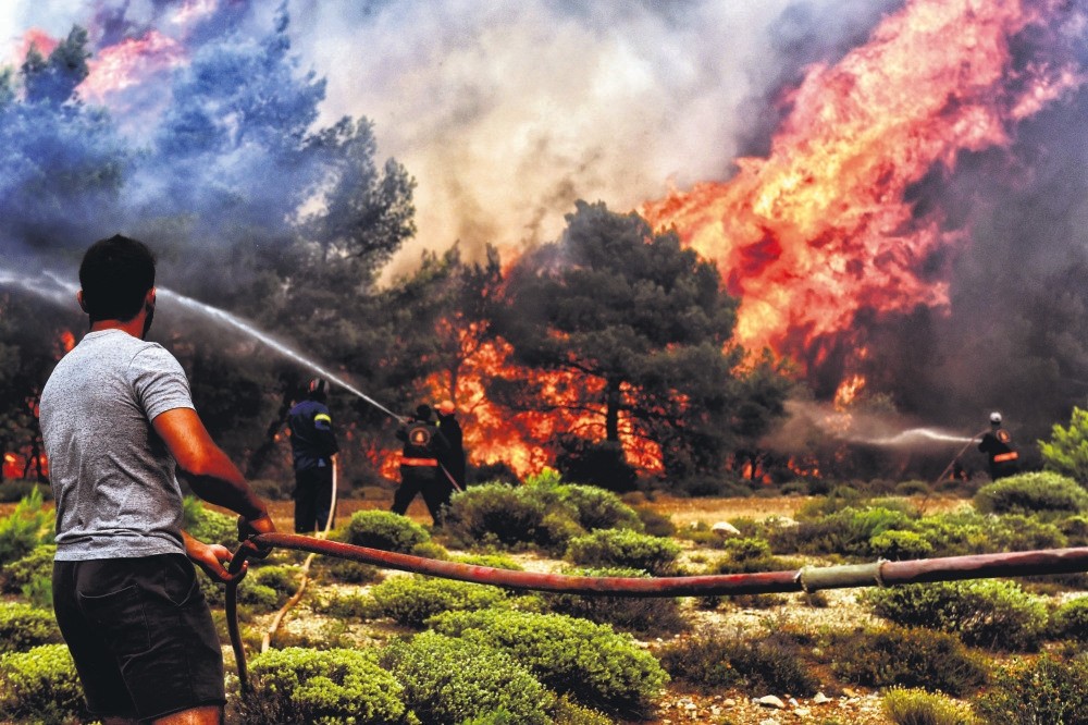 Firefighters and volunteers try to extinguish a wildfire raging in Verori, southern Greece, July 24.